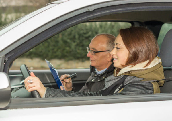 A man and woman in the driver 's seat of a car.